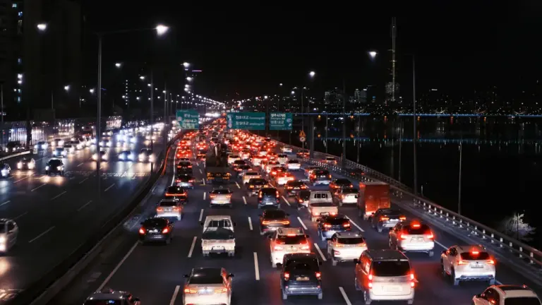 Intensyvus naktinis eismas automagistralėje su šviesų ruožais ir automobilių žibintais.