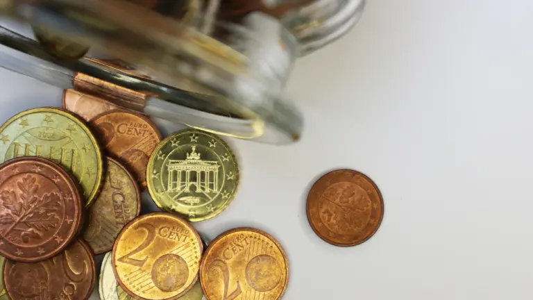 Euro monetos išbyrėjusios ant balto paviršiaus, vaizduojančios Lietuvos infliacijos ir ekonomikos temą.
