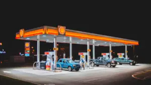 Šiuolaikinė degalinė naktį, kurioje automobiliai užsipila degalų į savo bakus.