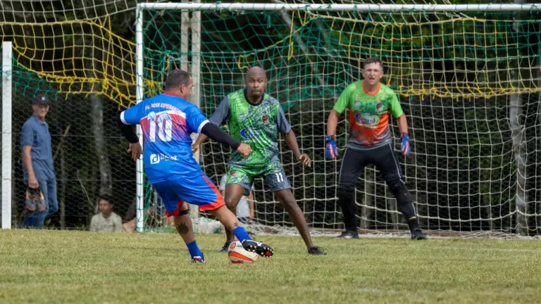Futbolo žaidėjai varžosi dėl kamuolio futbolo stadione prieš vartus.